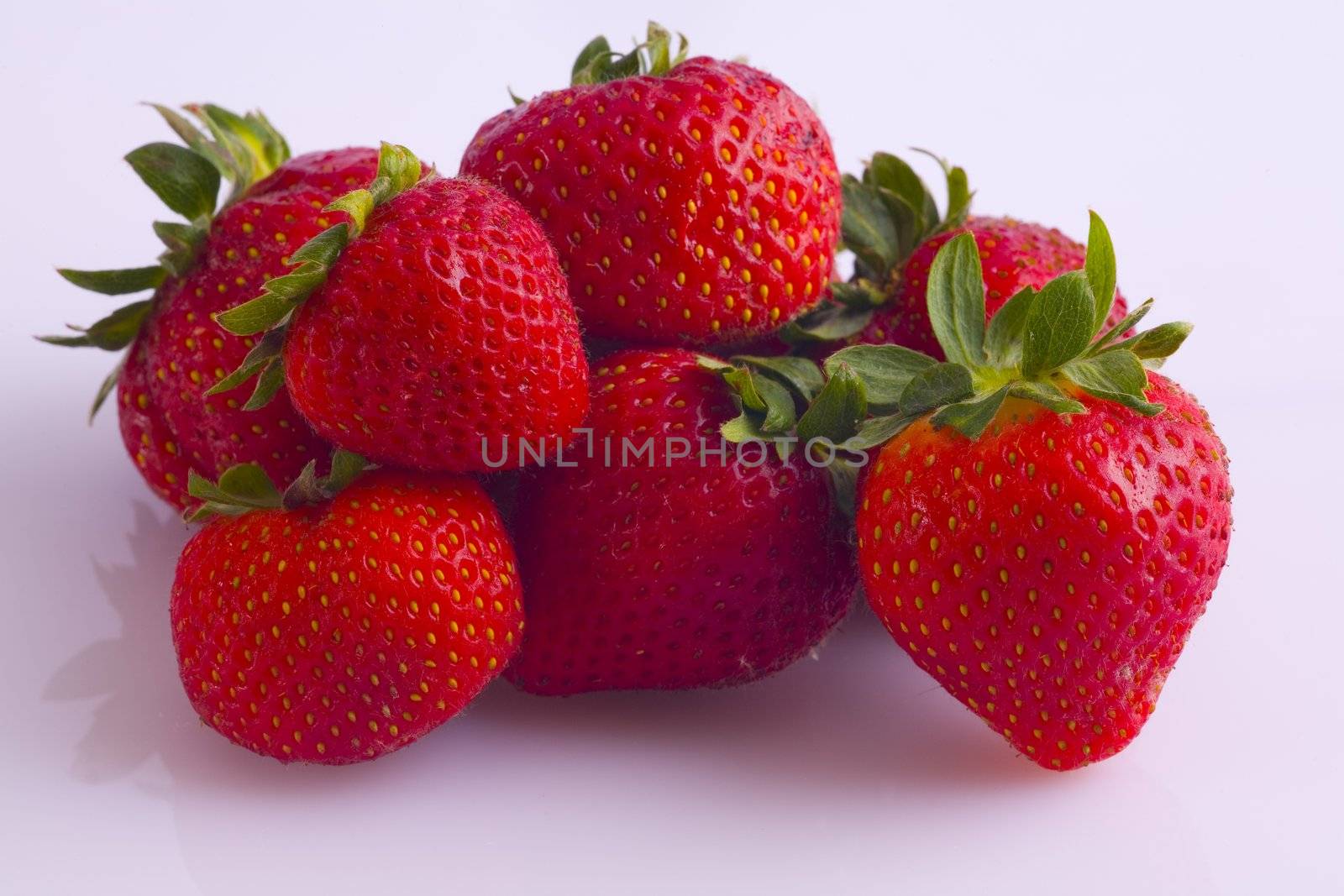 Strawberries red, plump, and juicy, in a small pile on a white background.