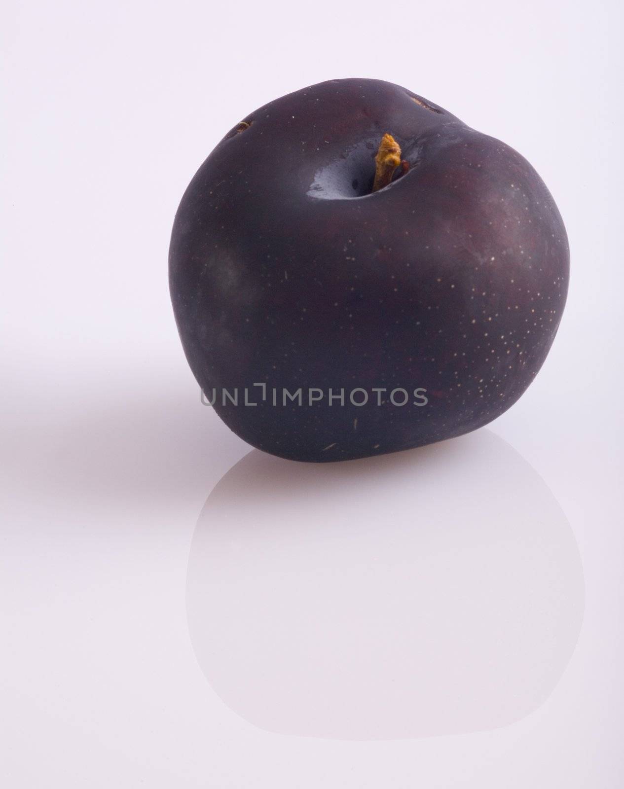 A plum reflecting on a white surface.