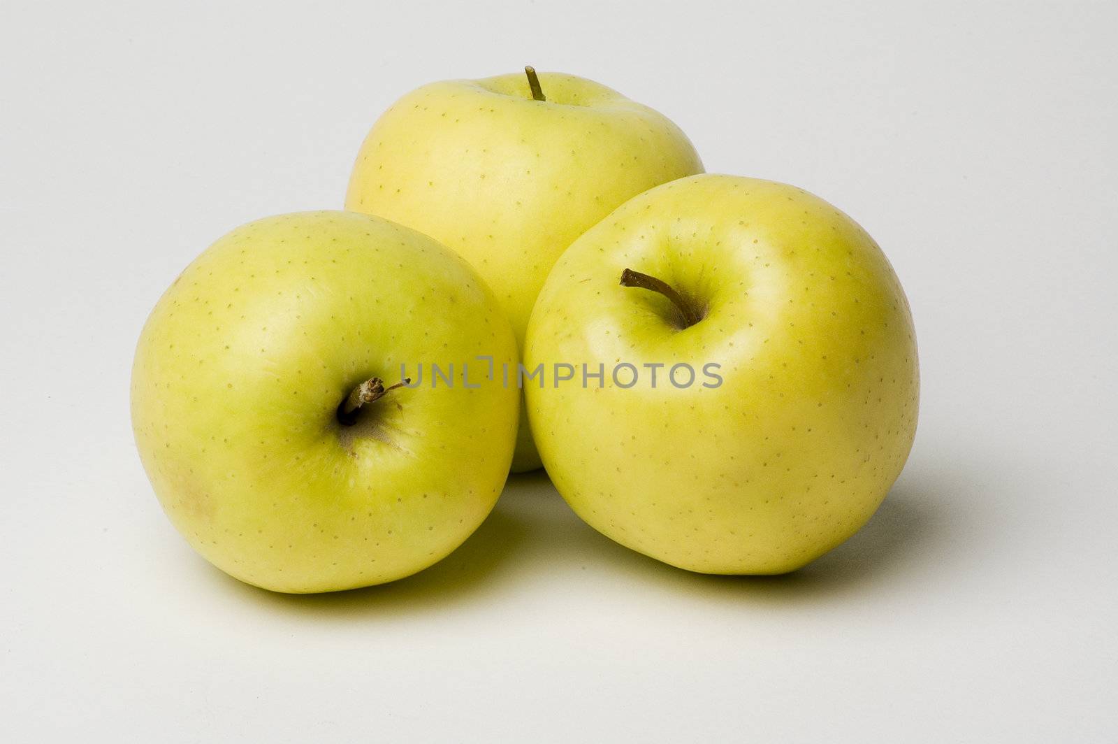 three yellow apples on a white background