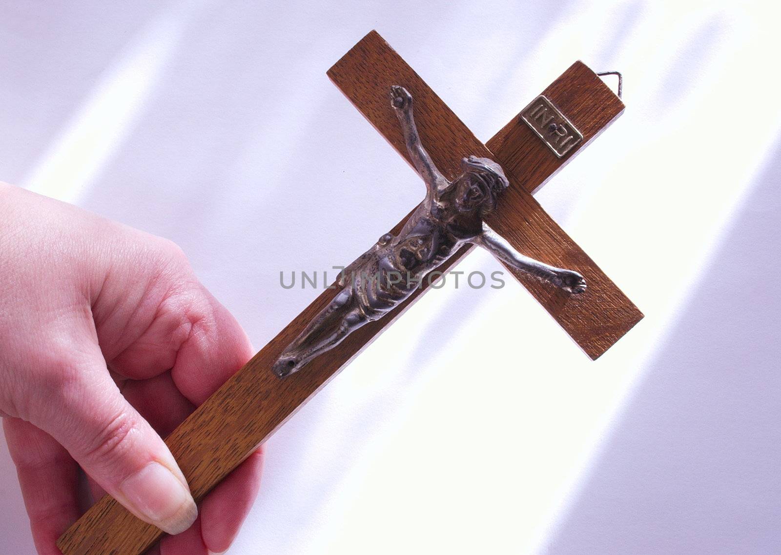 old wooden cross with christ being held in a hand