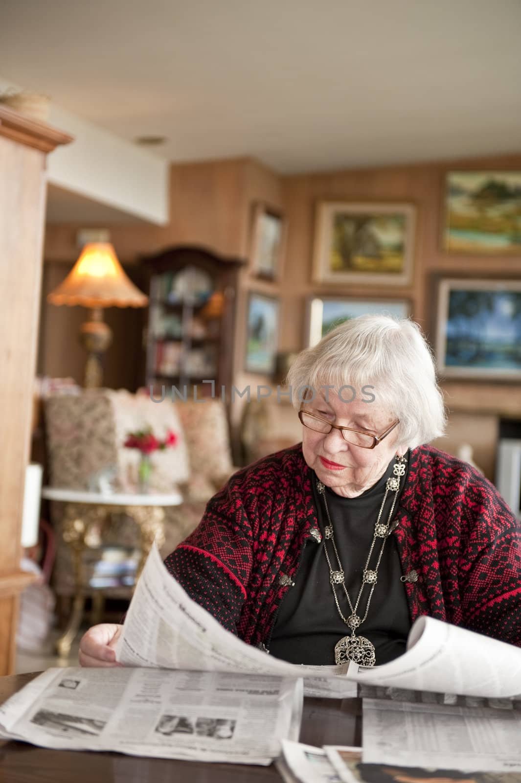 87 year old woman at home reading paper. USA