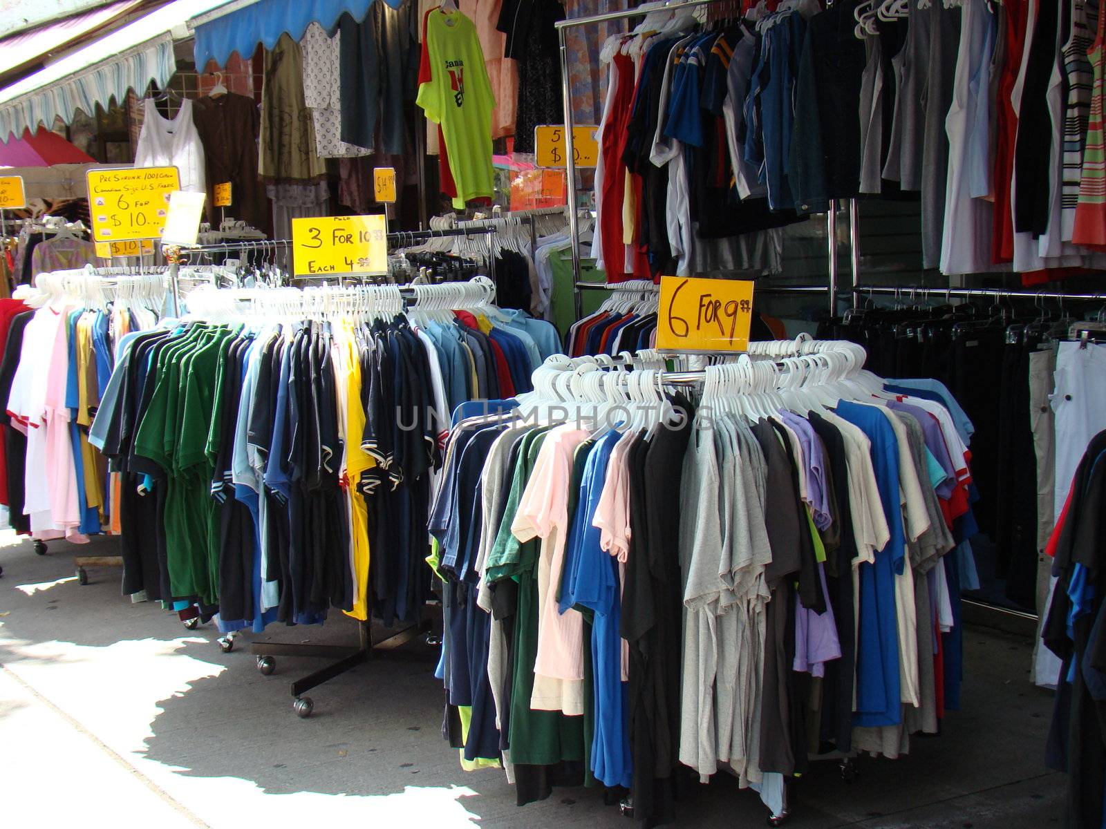 Racks Of Clothes With A Variety Of Colours at outdoor market by hicster