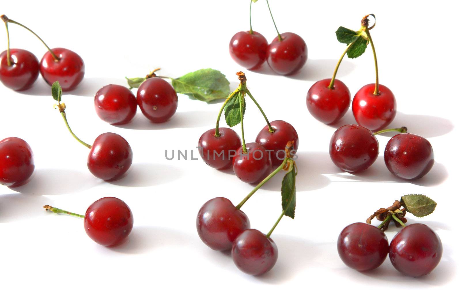 Ripe berries of a cherry of red color and their shadow on light background.