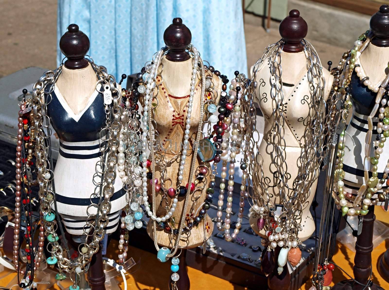 Collection of antique jewelery items on figurines in a flea market 