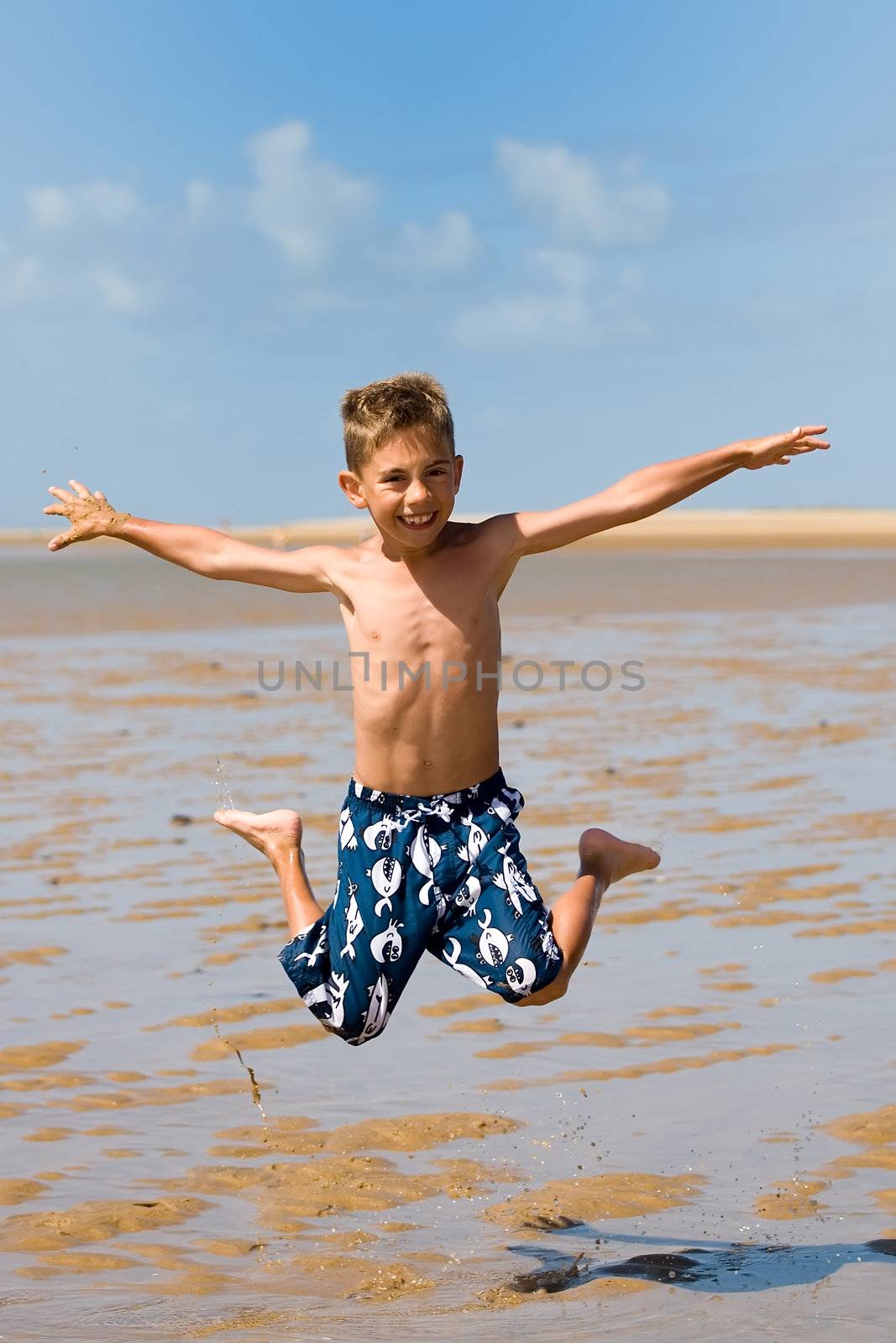 a boy jumping high on the beach