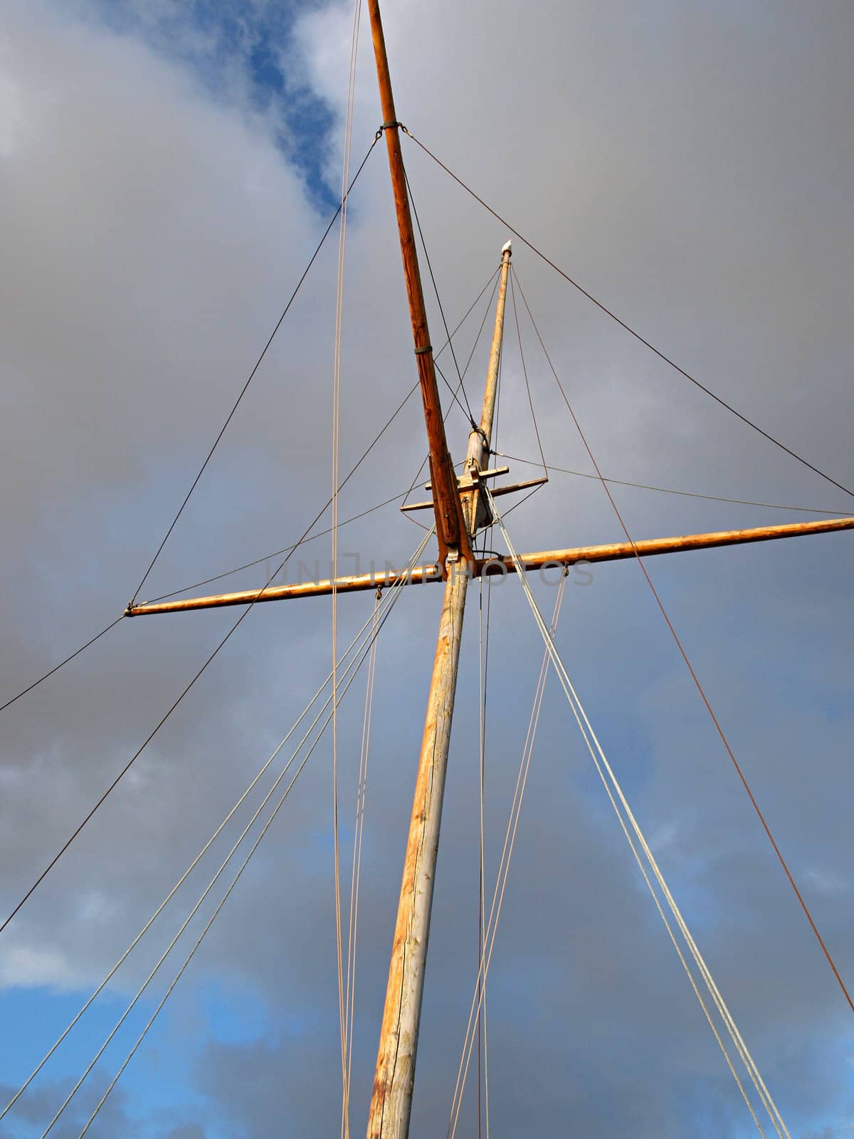 Wooden mast of an old sail boat with cloudy background  