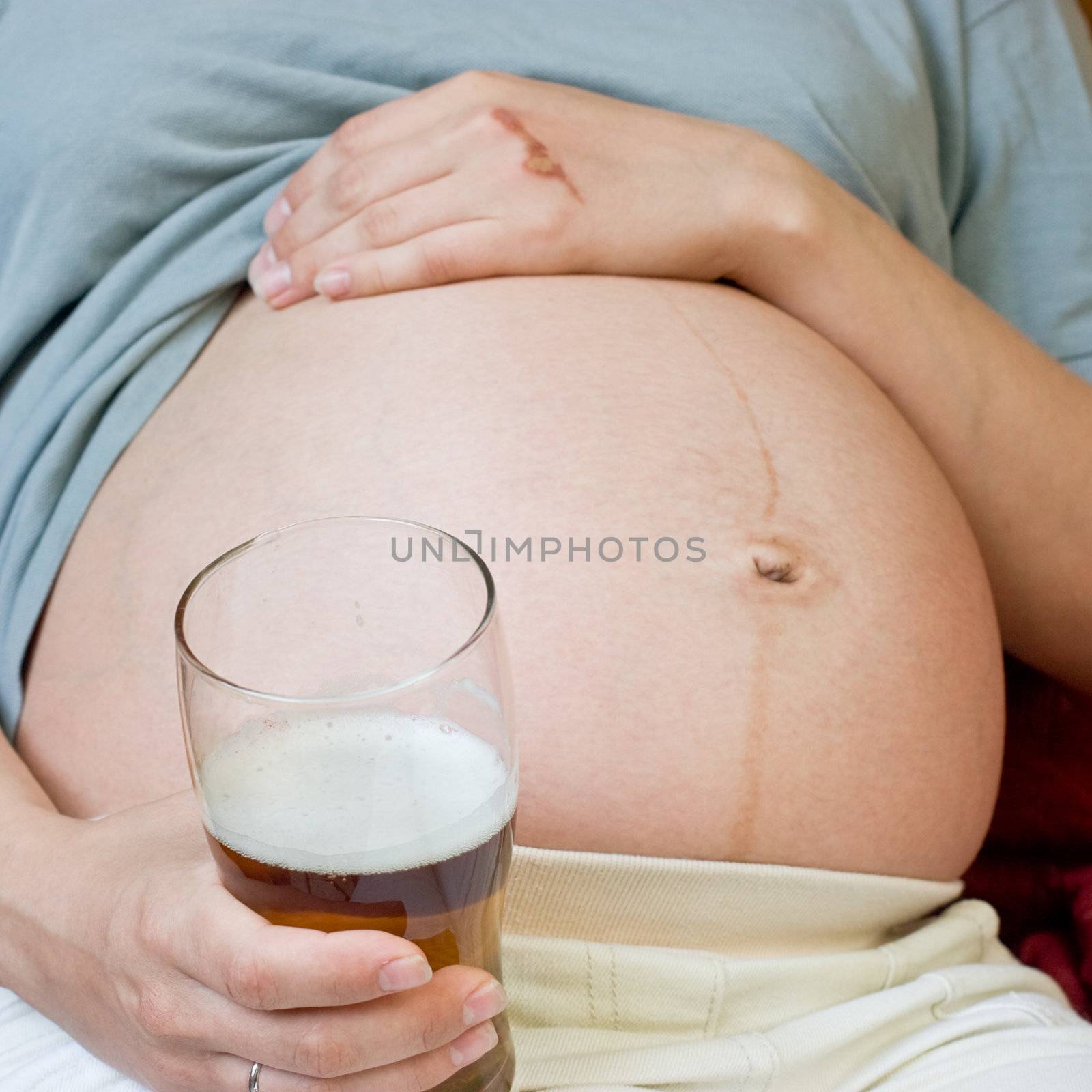 Young pregnant woman holding glass of beer