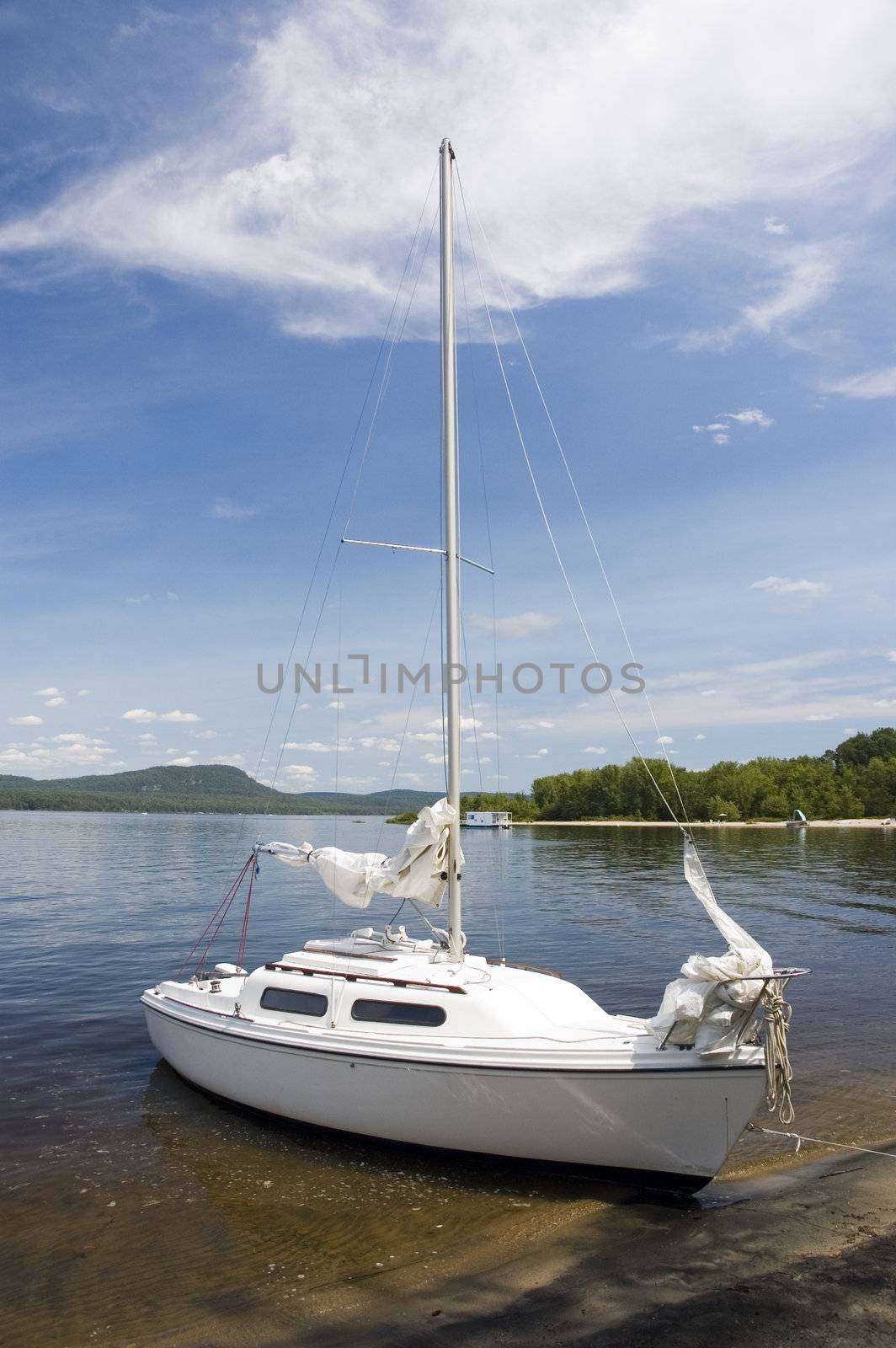 a small white sail boat near the shore