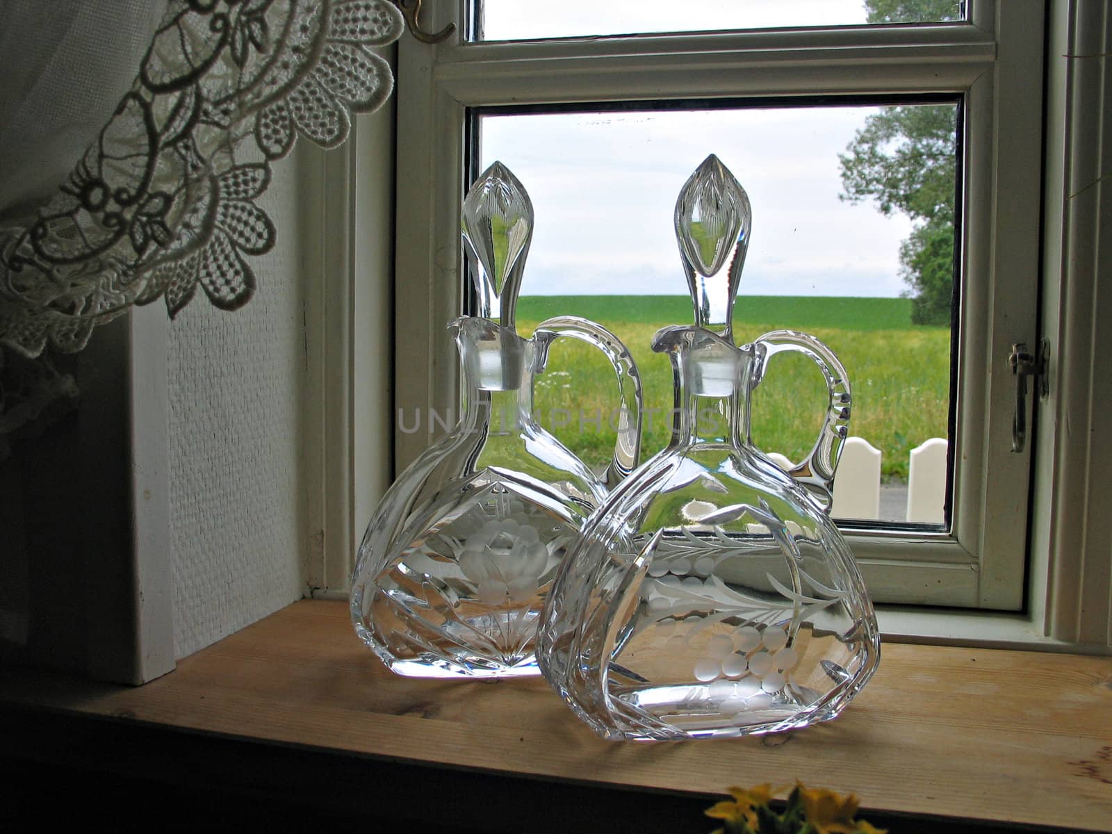 Decorative antique glass bottles on a shelf next to a window