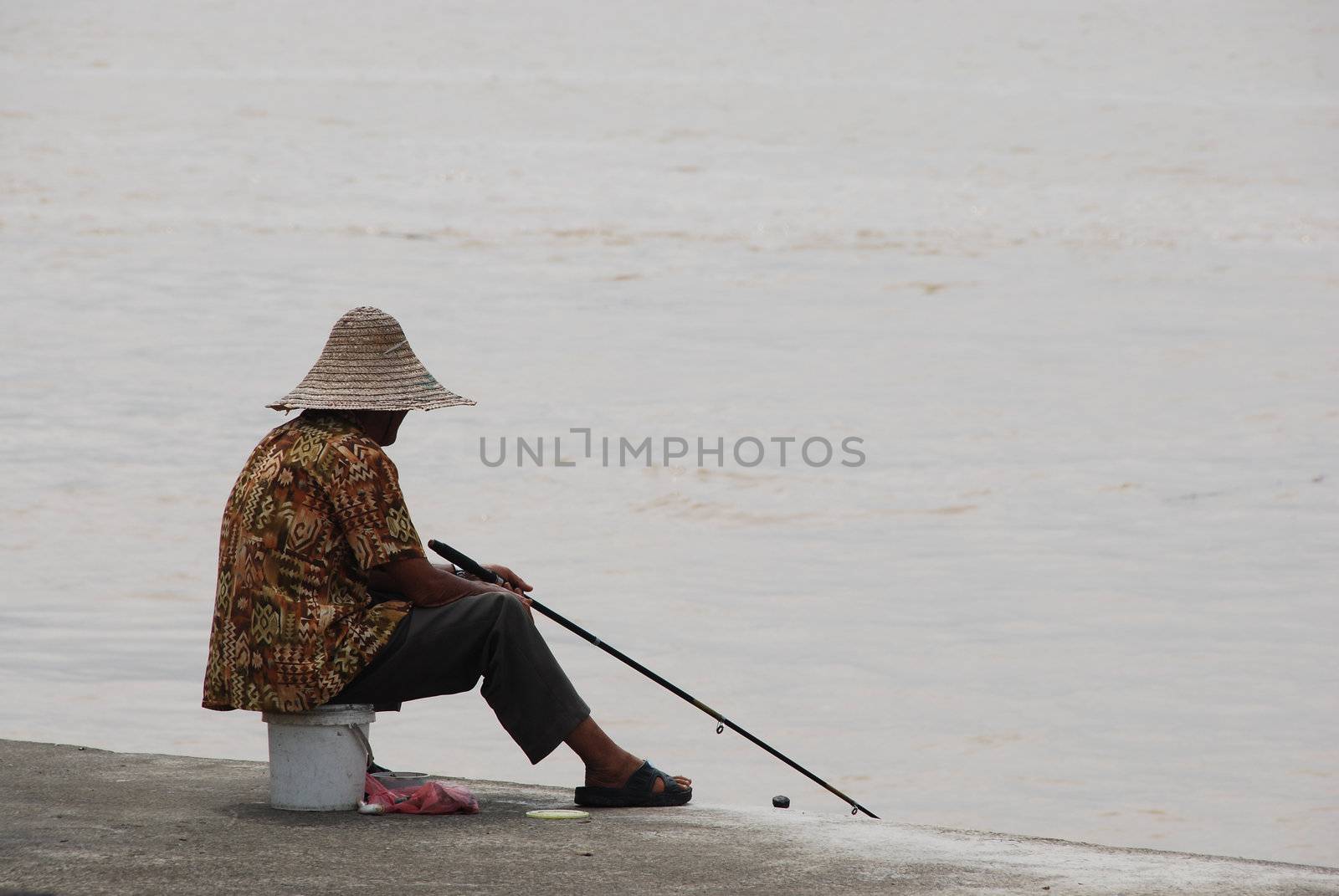 Asian man fishing from a pier