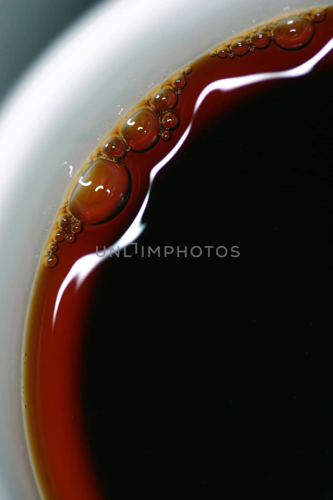 Extreme close-up of coffee with beautiful highlights and bubbles- could also be used as an image of tea
