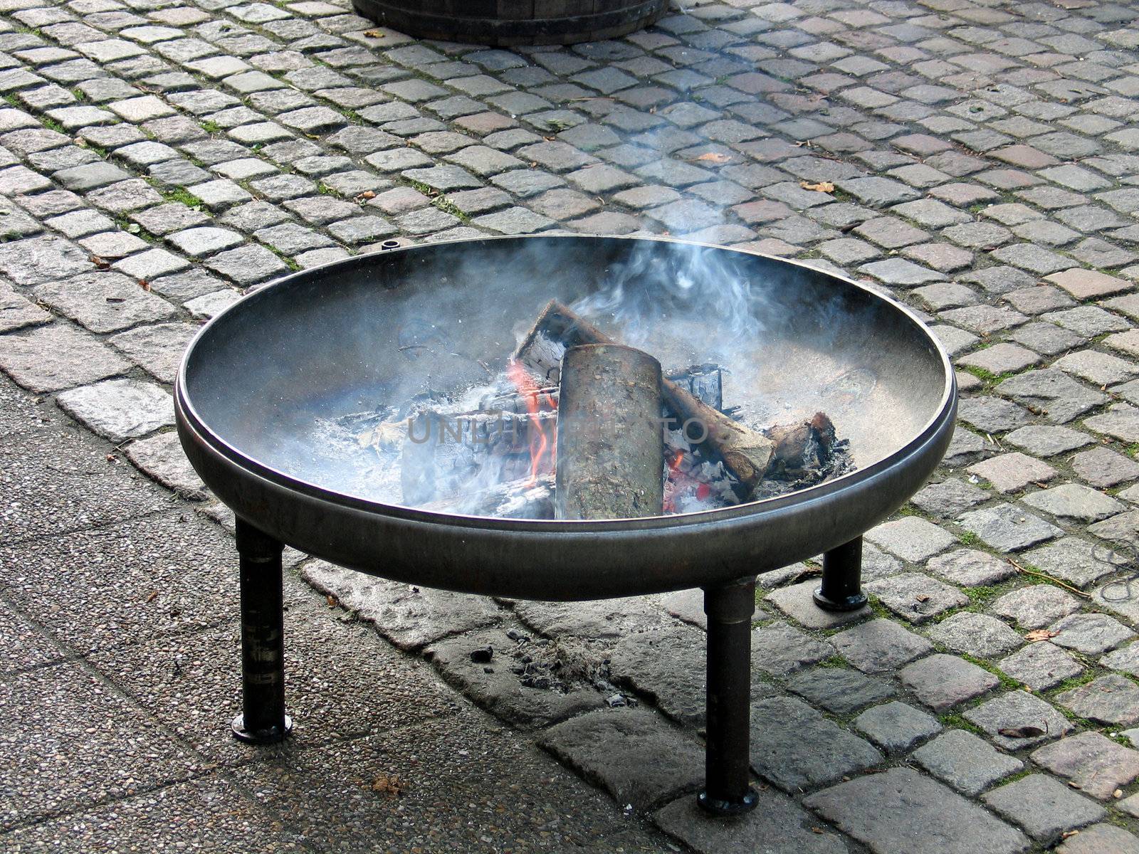 Fire pit in classical design made from copper with burning logs