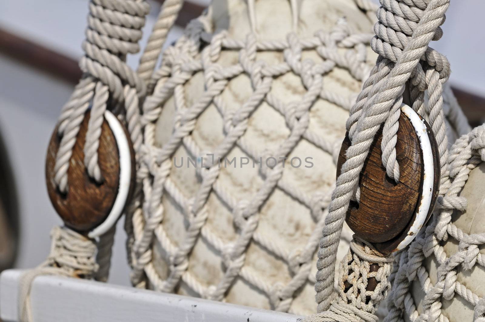 Close-up of old blocks on an sailboat with bumpers covered of rope net