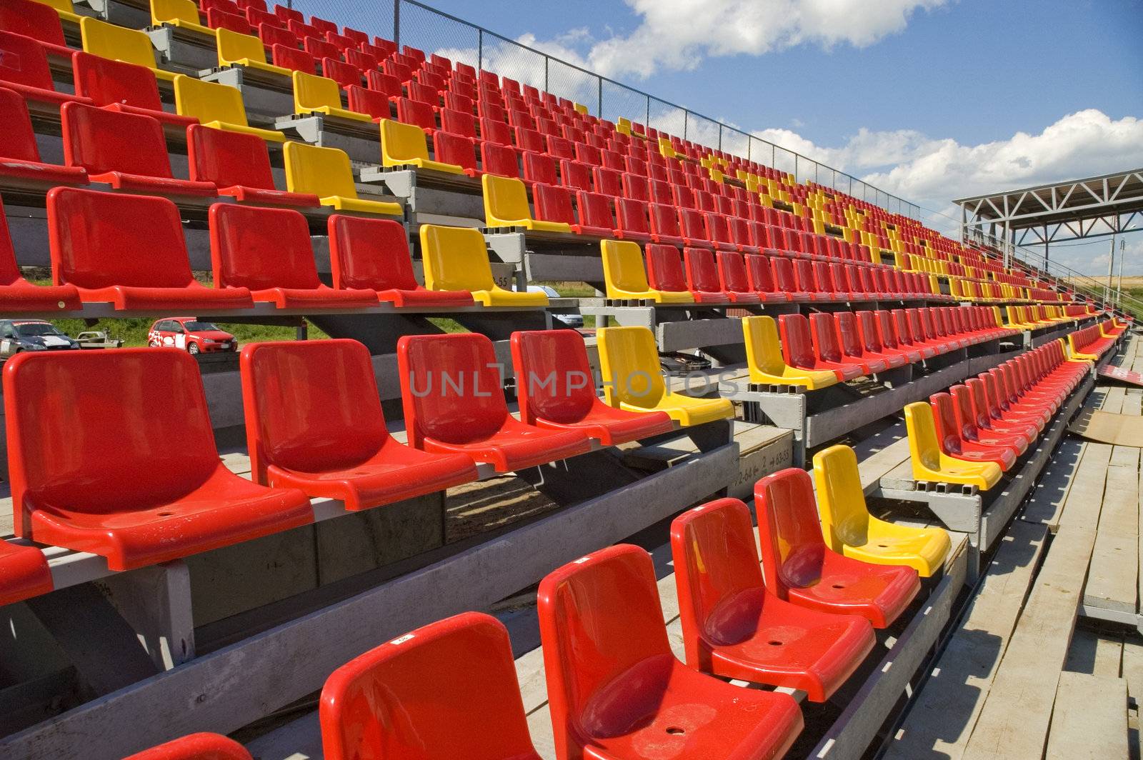 Red and yellow seats on a background of the sky with clouds.
