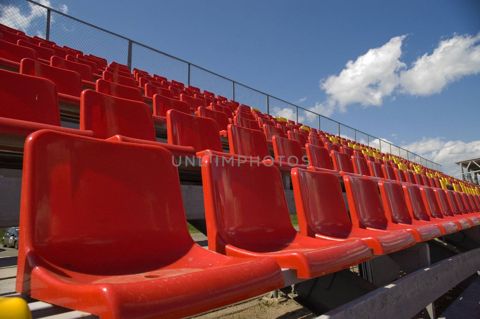 Red seats on a background of the sky with clouds.
