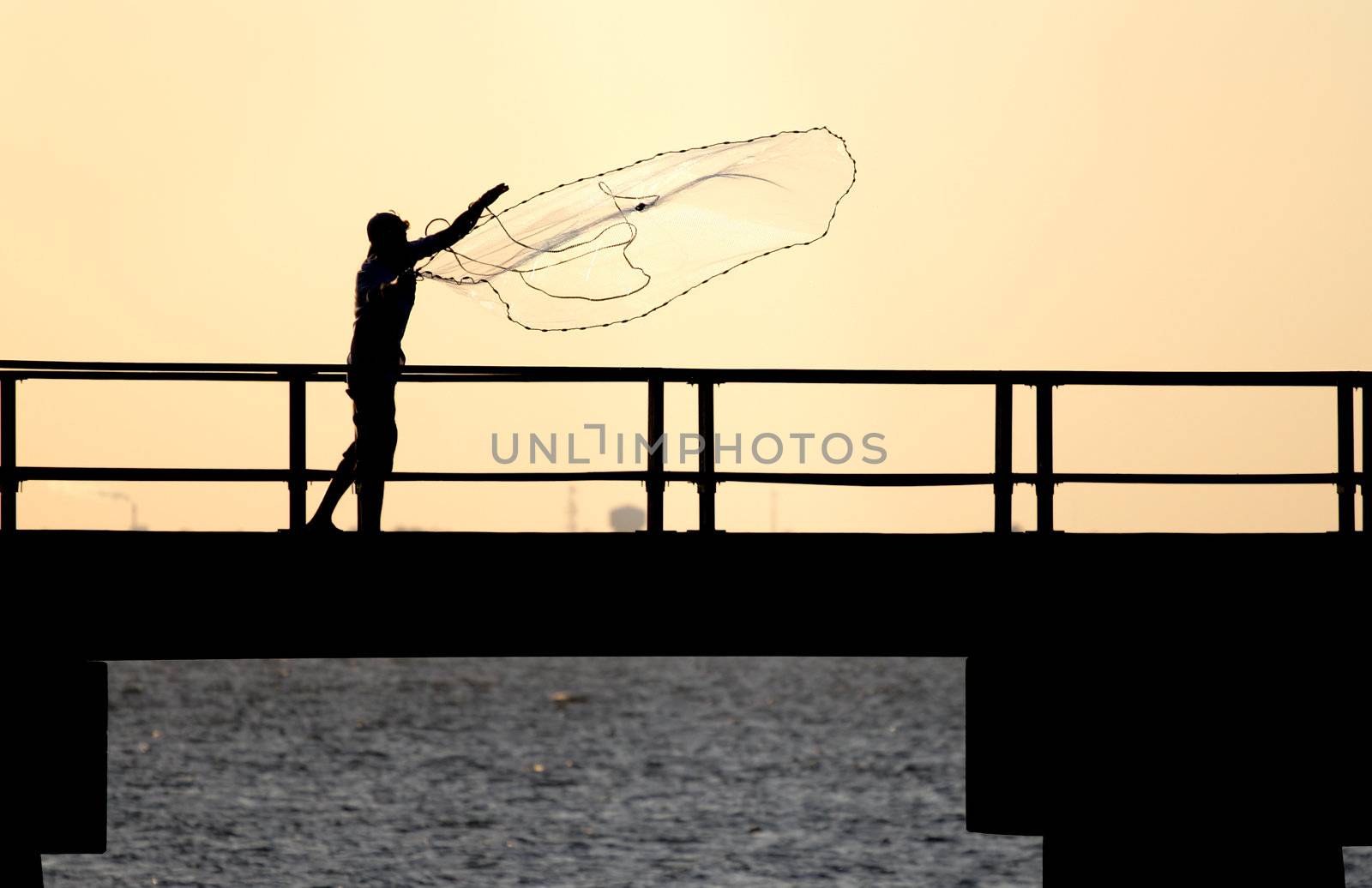 Fisherman tossing a net from a pier.