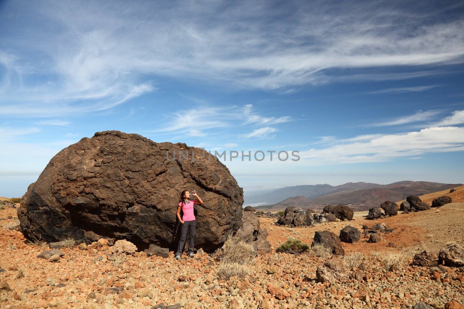 Tenerife - Woman hiking on Teide. A view of a female backpacker standing by one of the many big black Teide Eggs or in spanish: Los Huevos del Teide.