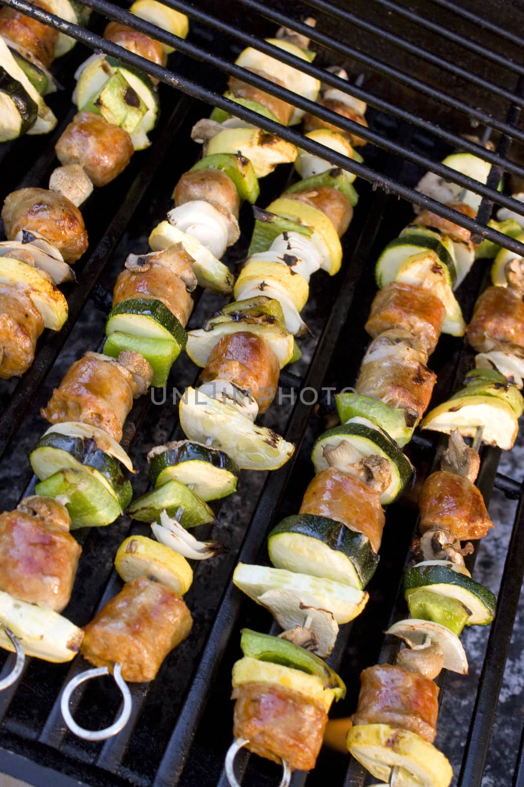 Sausage shish kebabs on skewers, cooking on the grill.