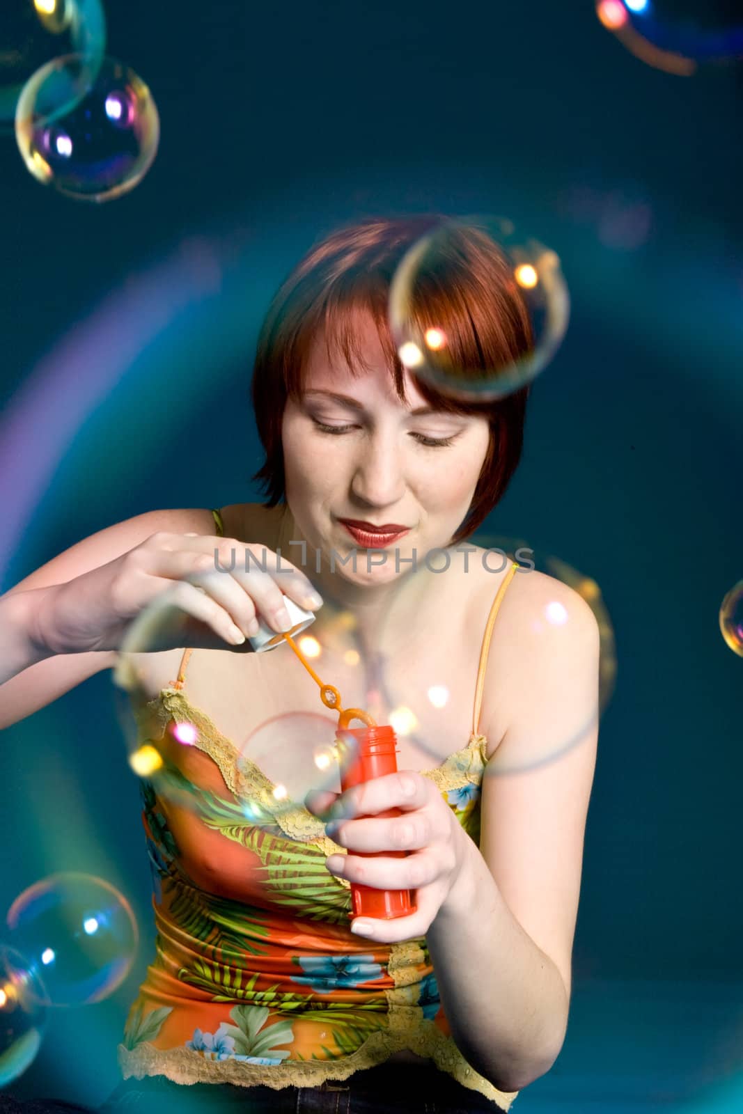 Red haired girl is trying to blow some big bubbles