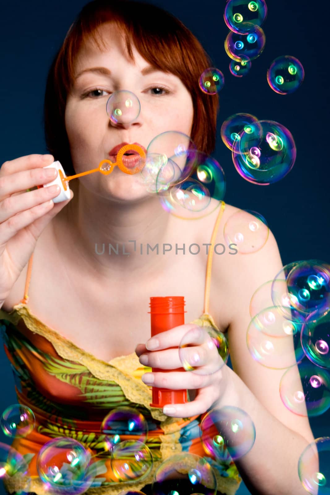 Red haired girl is trying to blow some big bubbles