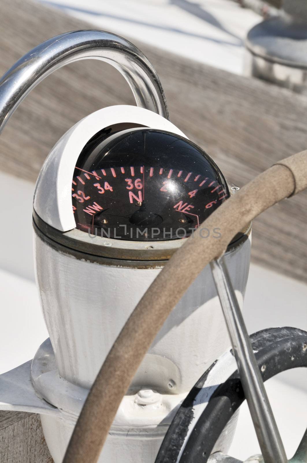 Close-up of a compass and steering wheel on the deck of a sailboat