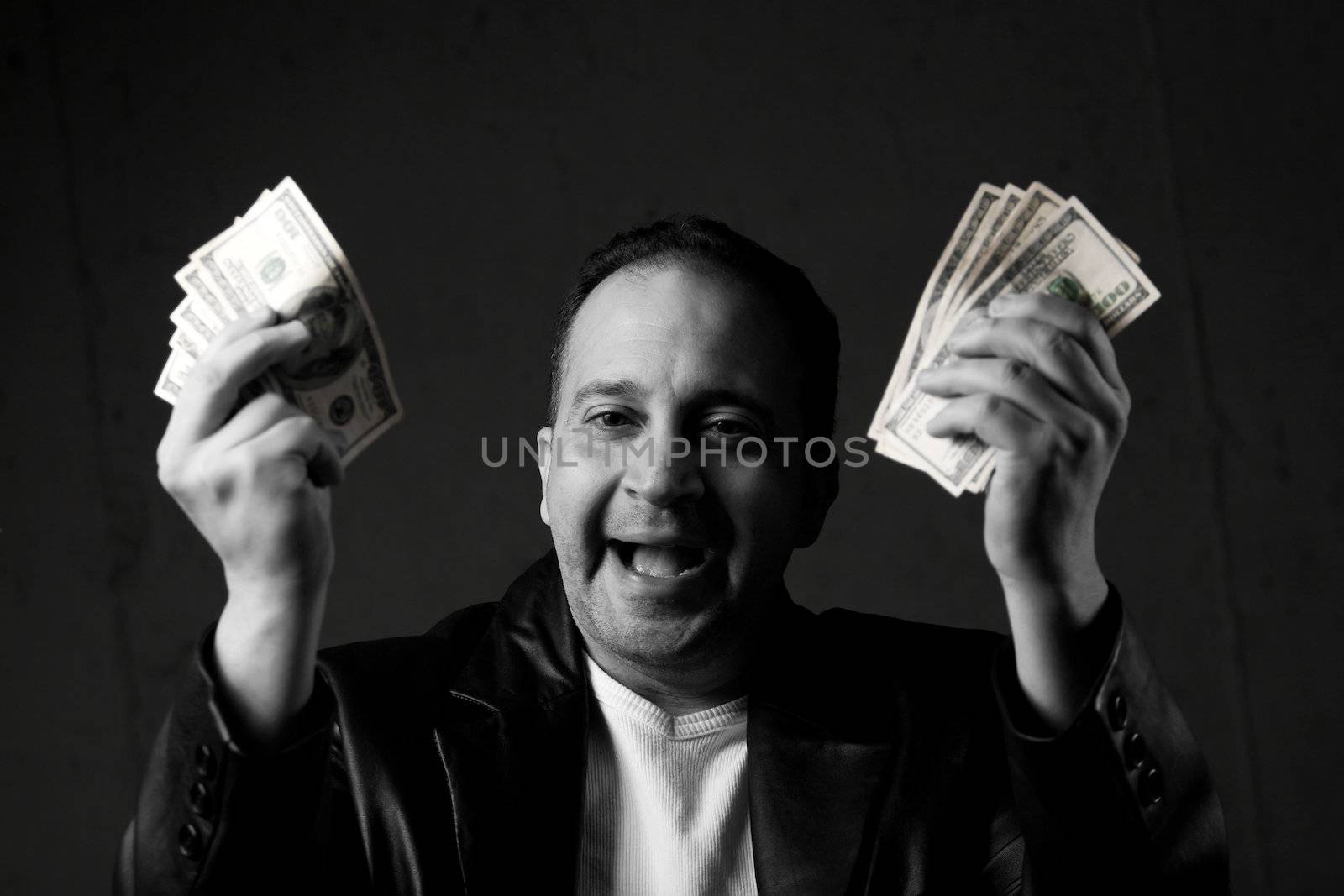 A man celebrating holding handfuls of green American cash with selective color. Shallow depth of field with focus on the face.