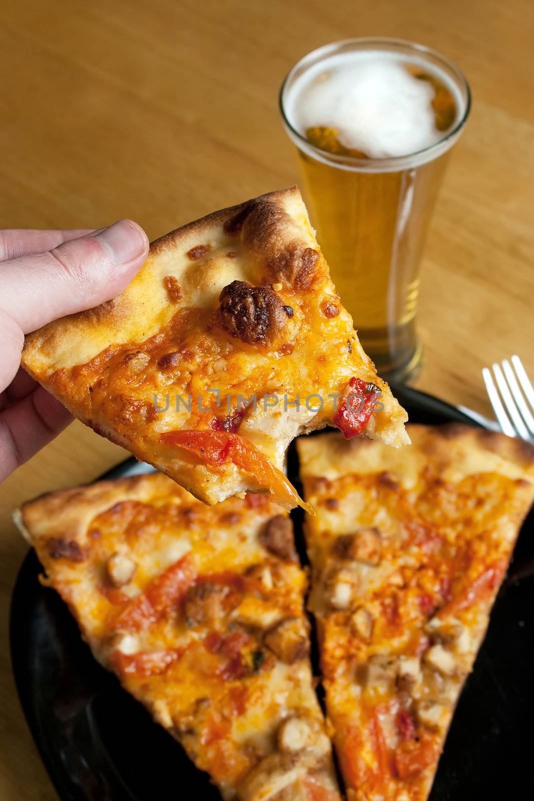 A male hand feeding himself buffalo chicken pizza from the first person point of view.  Shallow depth of field.