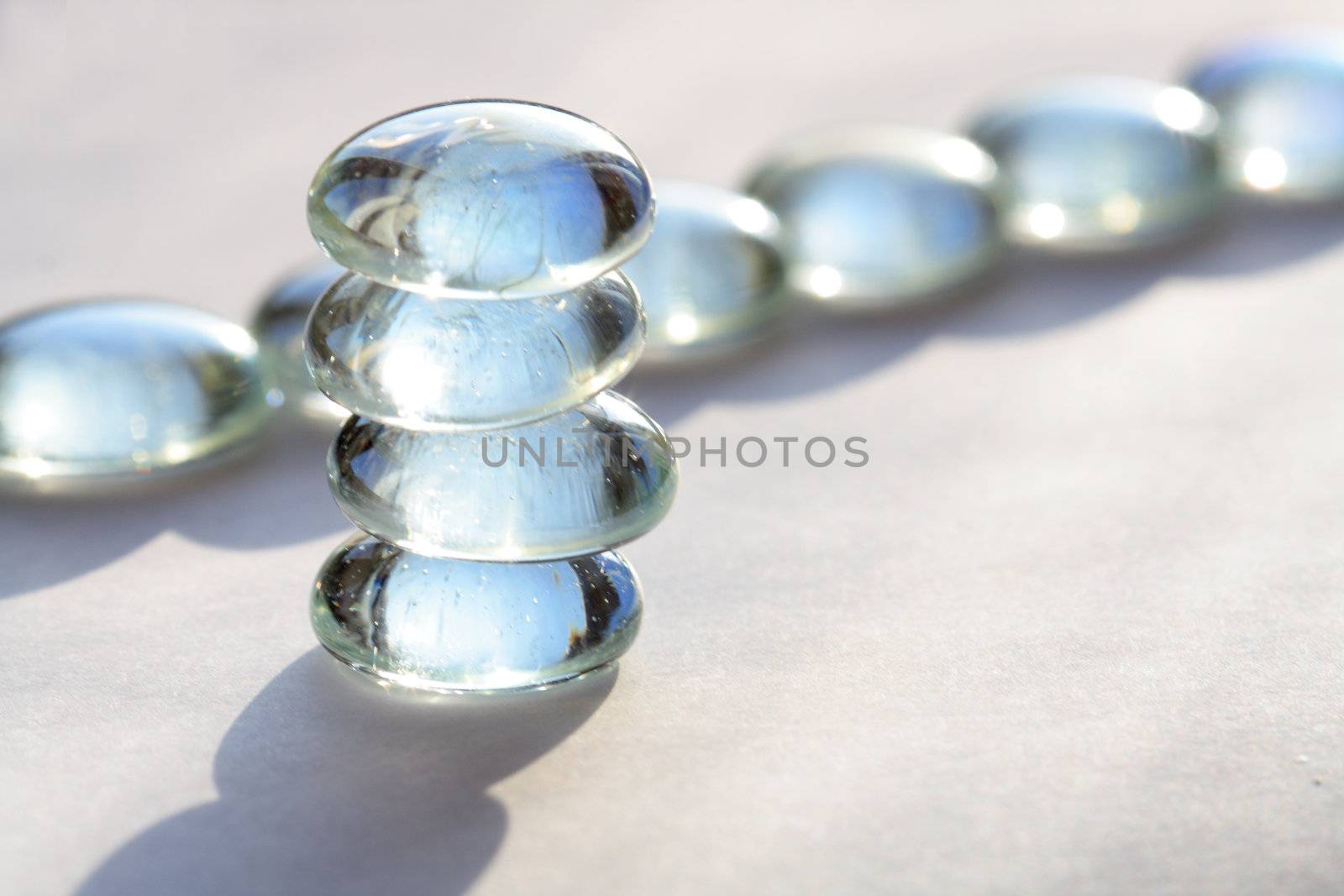 Stack of four glass stones on backround with glass balls lying in a row