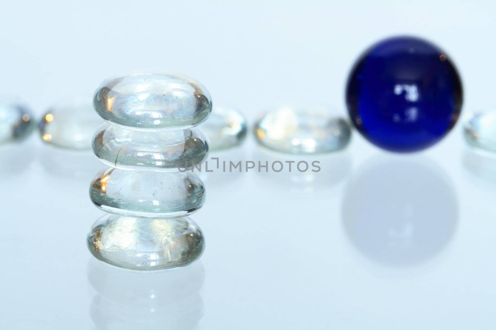 Stack of four glass stones on backround with glass balls lying in a row