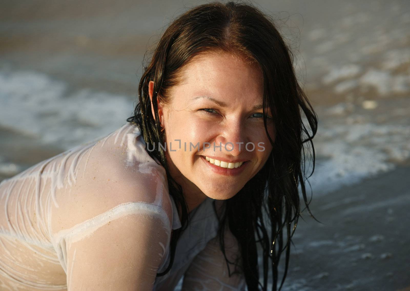 The happy girl in a wet dress at coast of the sea