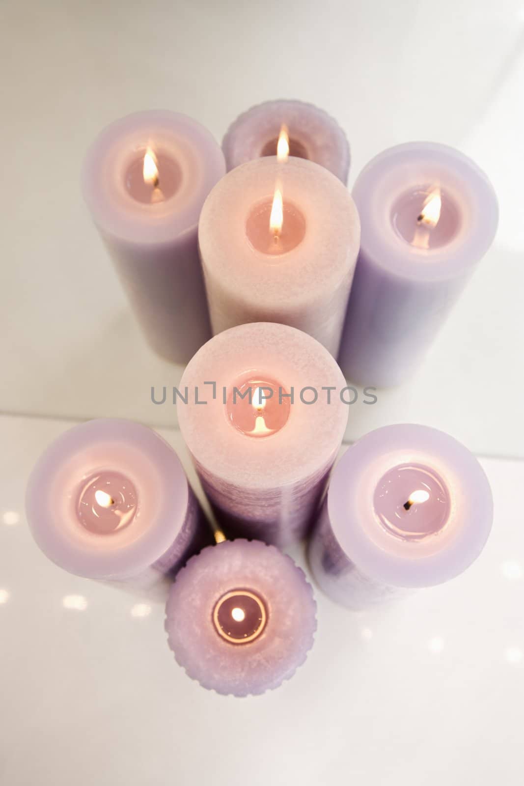 Overview of purple burning candles in front of mirror.