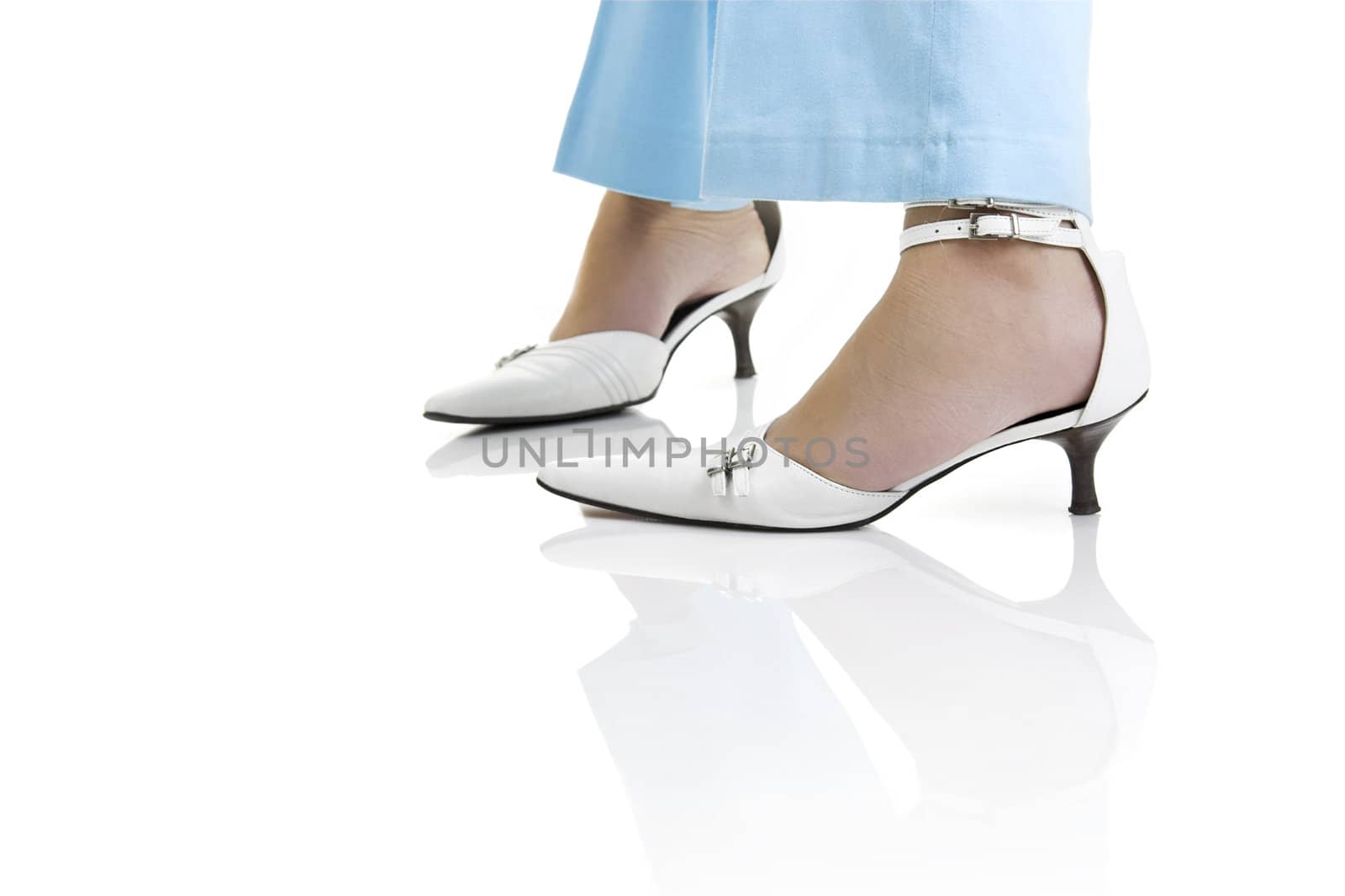 Woman legs with beautiful white shoes on a white background with reflection