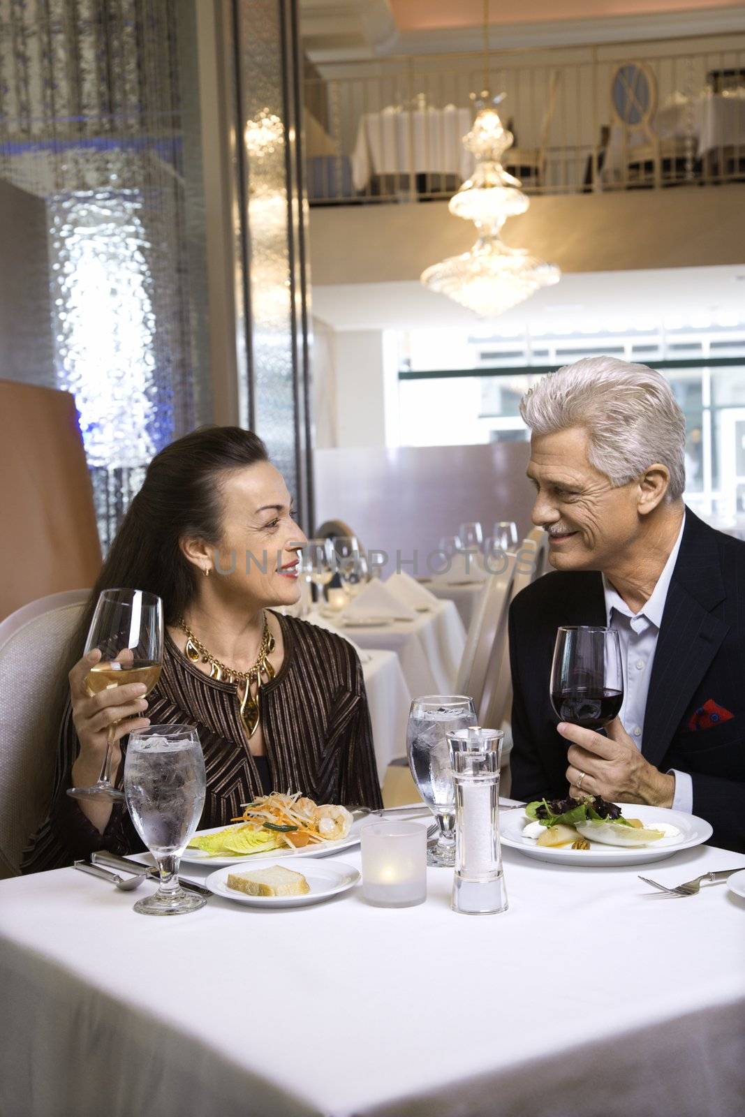 Caucasian mature adult male and prime adult female sitting at restaurant table.