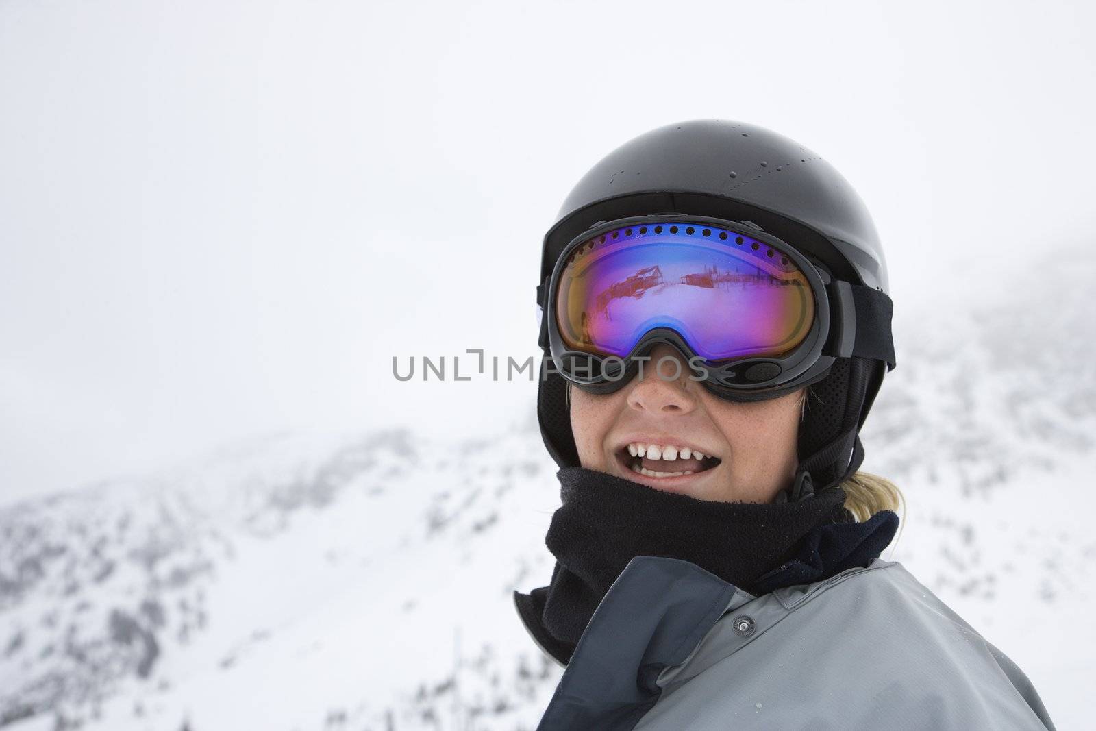 Caucasian teenage boy skier in helmet and goggles at ski resort on mountain.