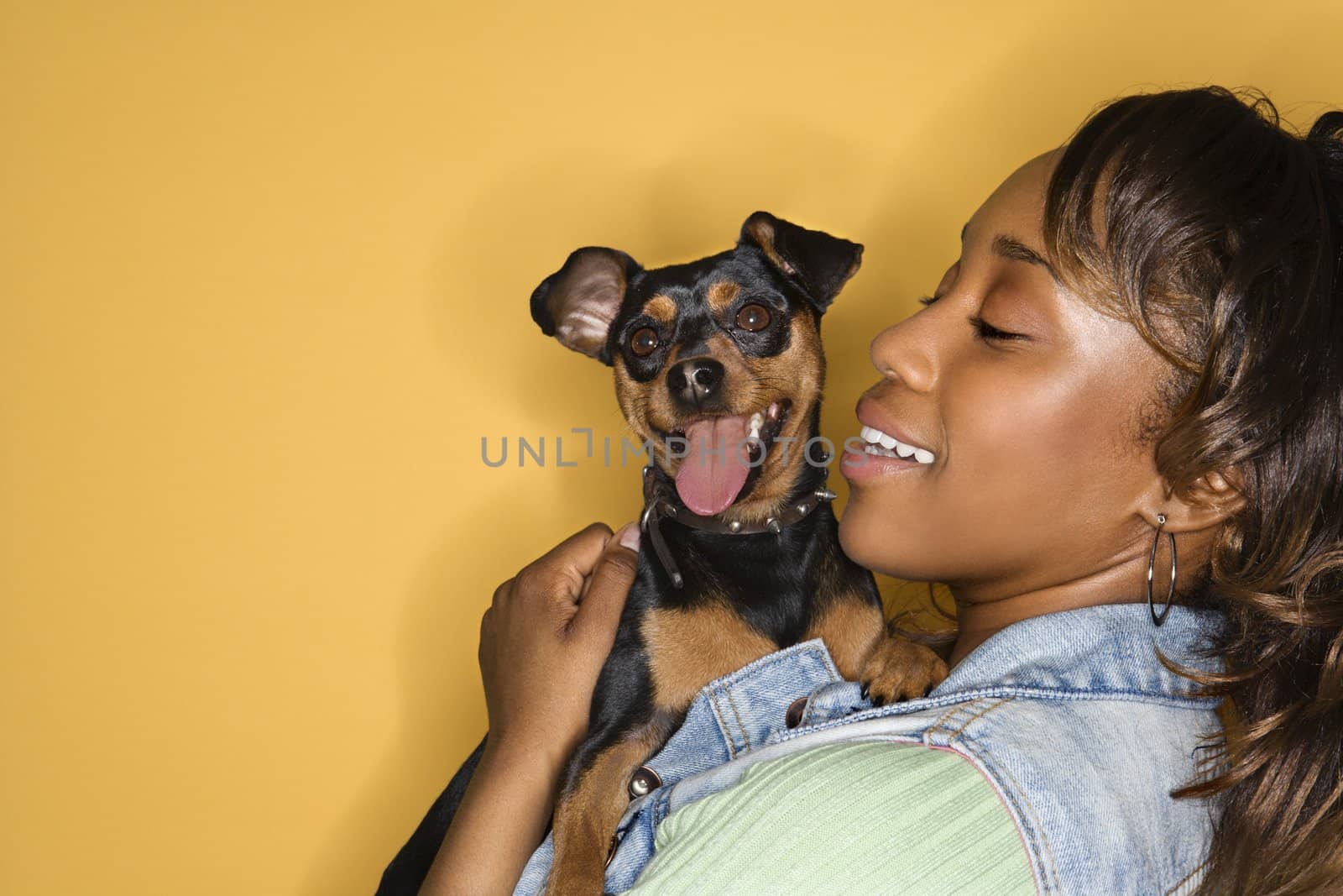 African American young adult female holding Miniature Pinscher dog.