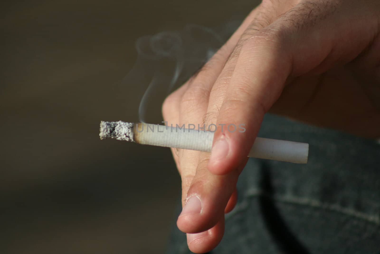 Close up of a hand holding a cigarette.