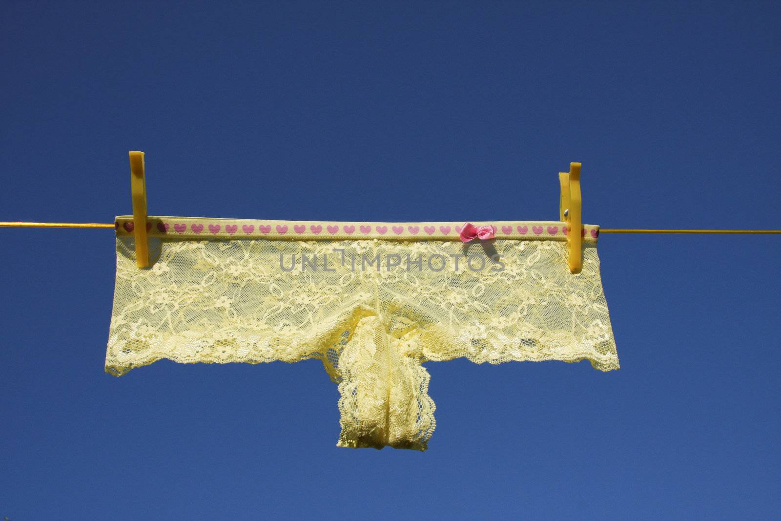 Clothes on washing laundry line, yellow lingerie, blue sky