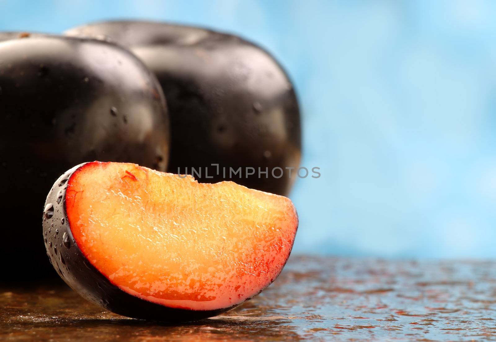 Fresh black plum slice on a stone counter.