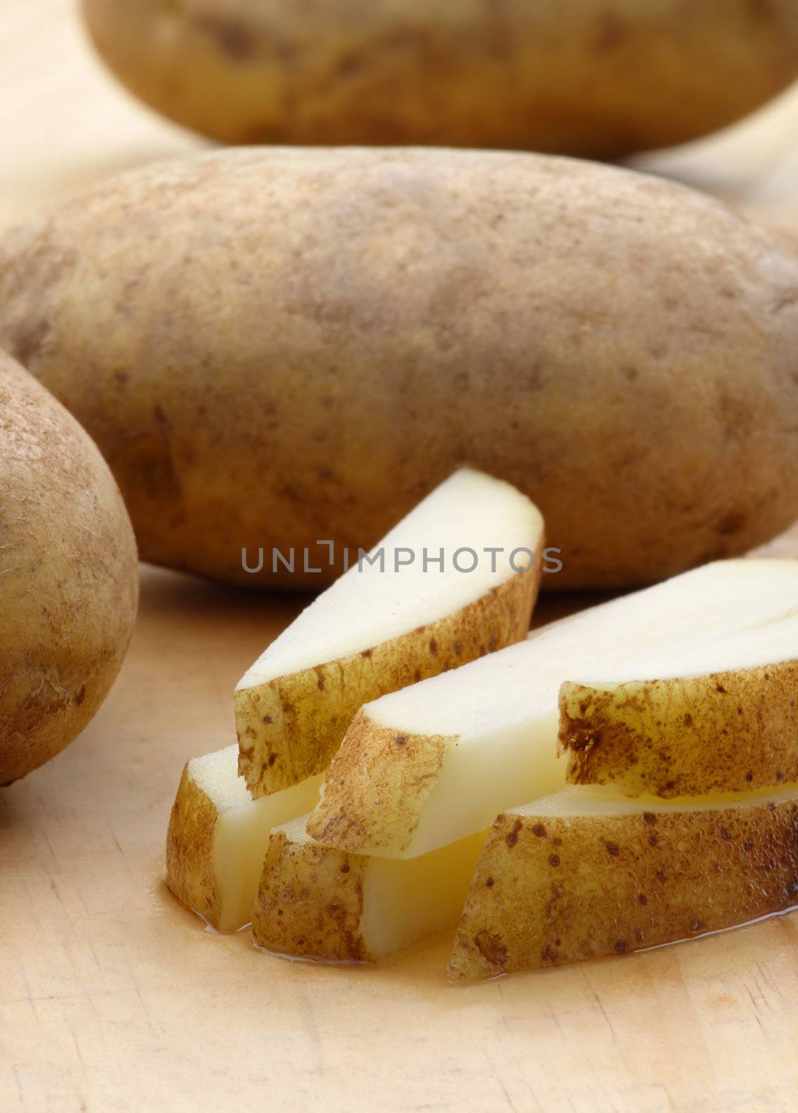 Fresh cut potatoes on a wooden cutting board.