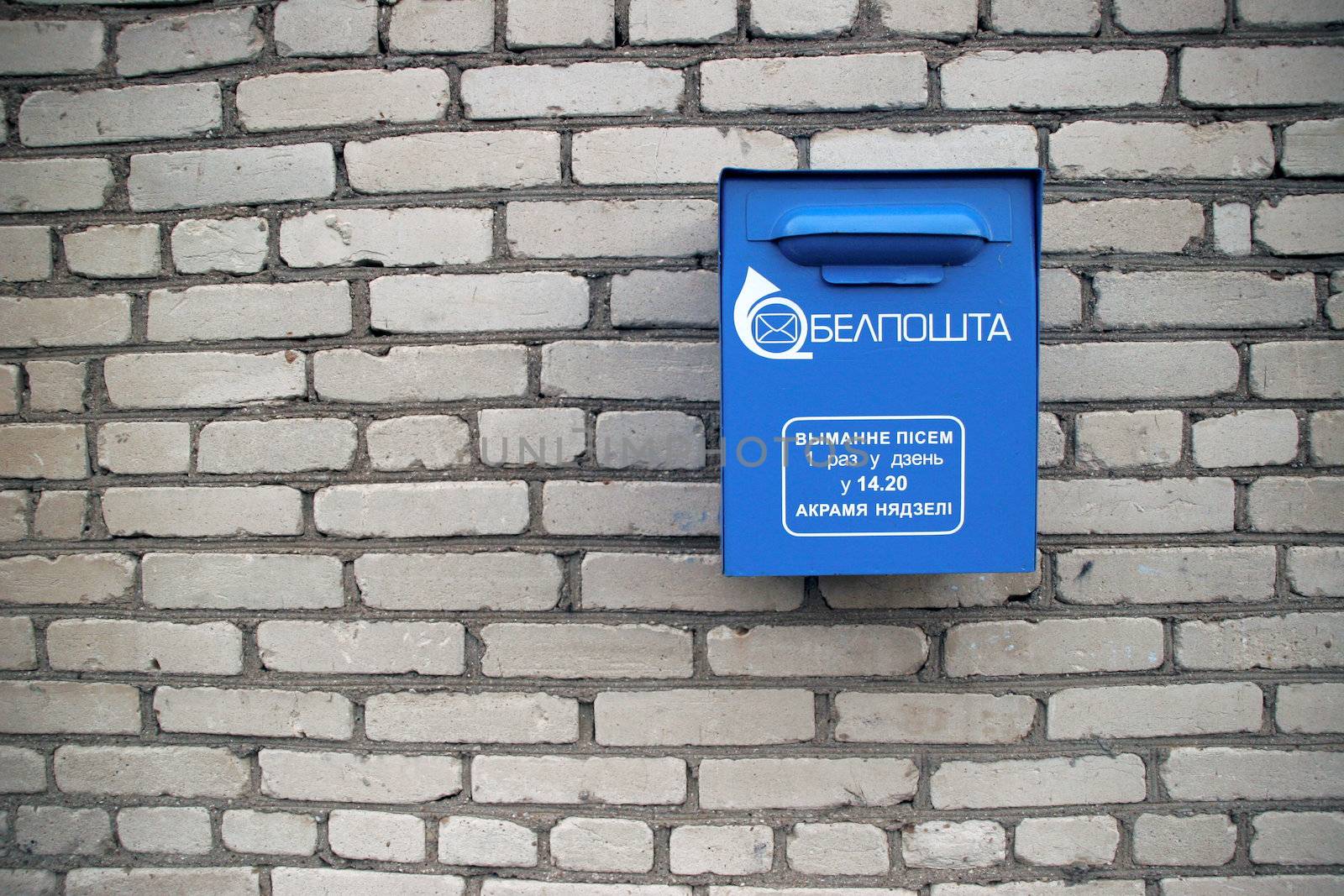 belarus postbox against white brick wall, blue box, postal symbols