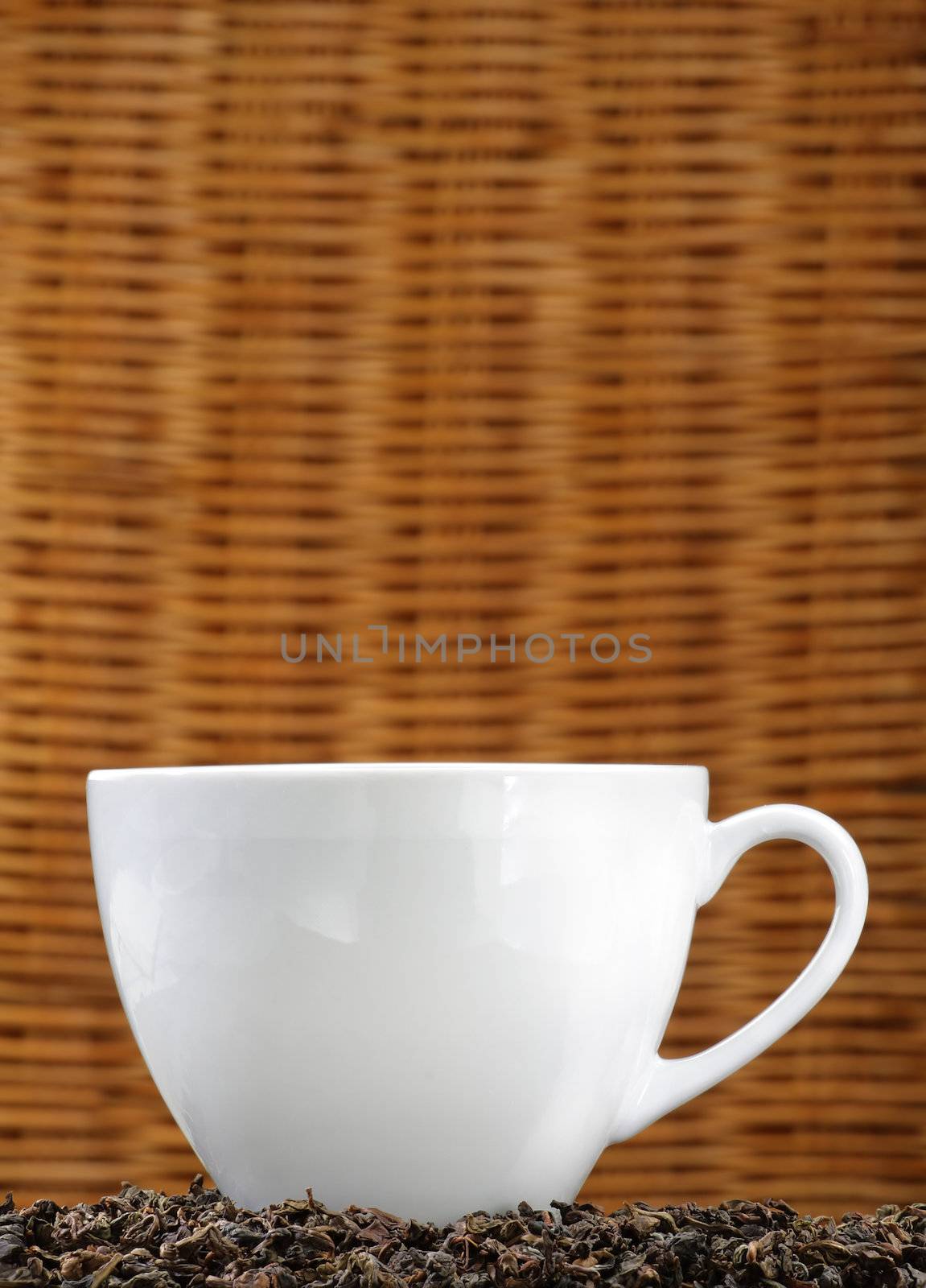 White tea cup on a bed of tea leaves with copy space.