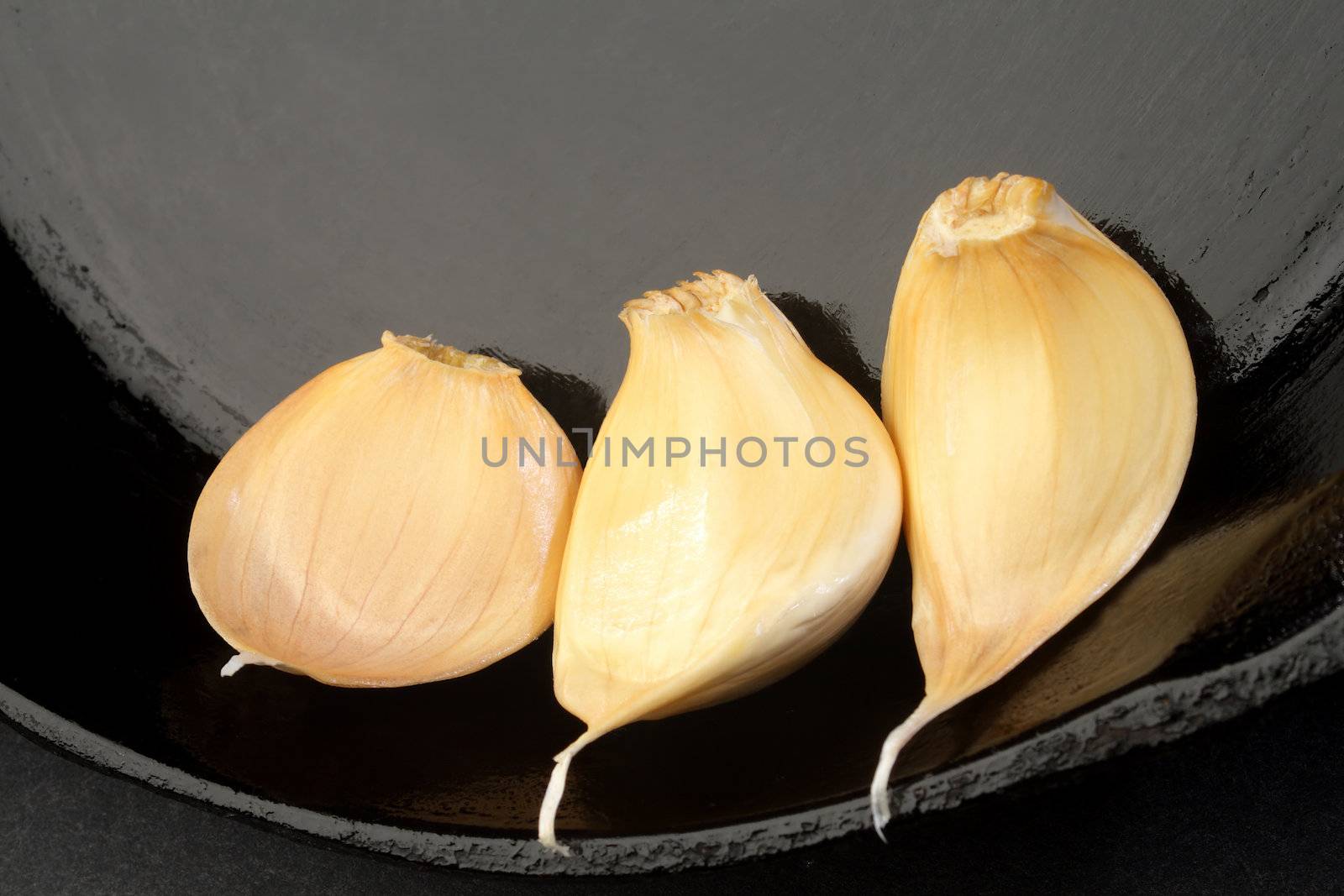  Three Cloves of garlic in a cast iron skillet.