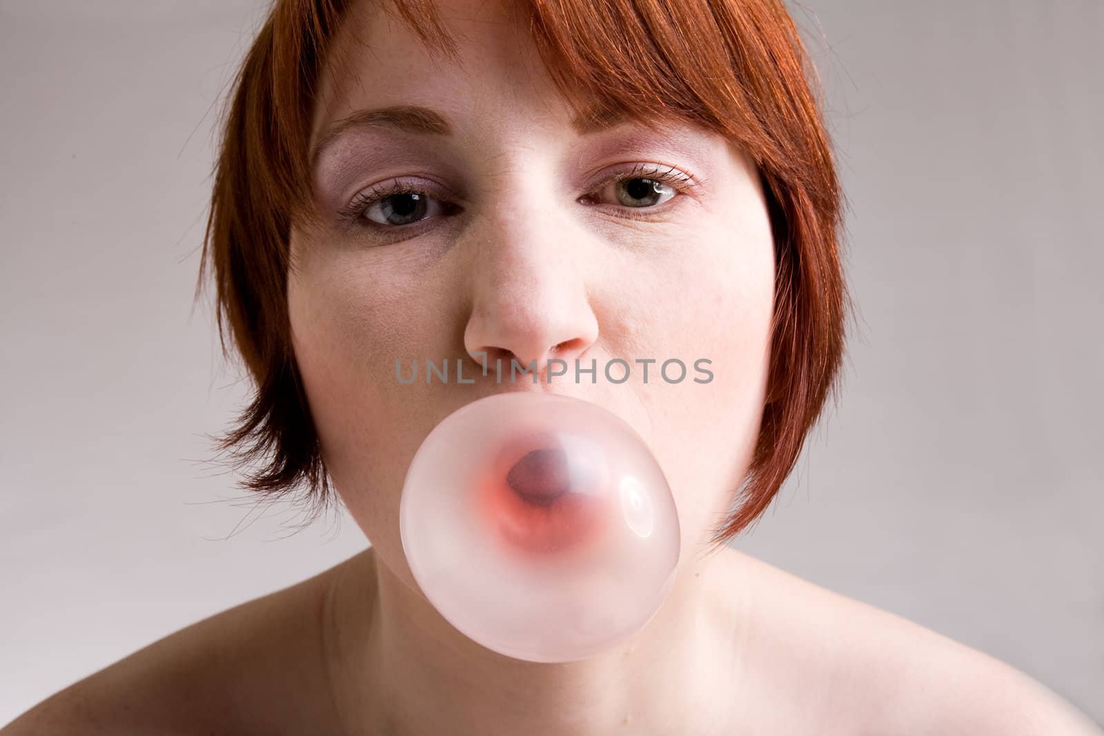 Red haired girl is eating fresh bubblegum
