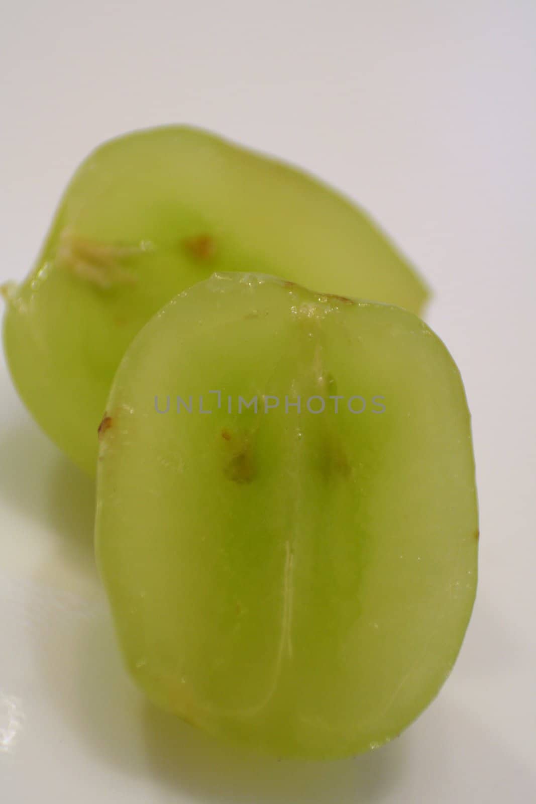 A very close up detail of a sliced grape on a white background.