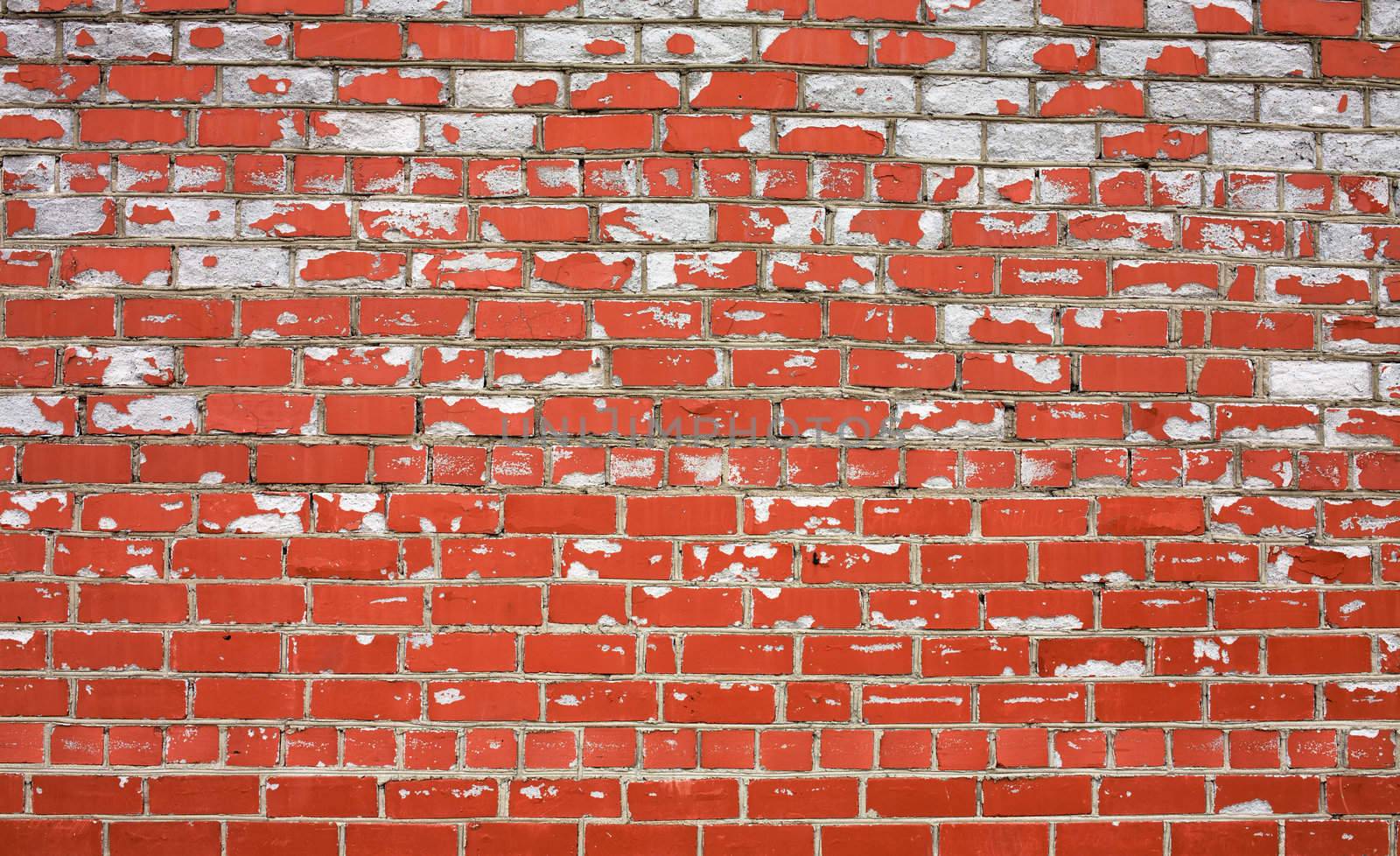 Decayed brick wall covered by a red paint