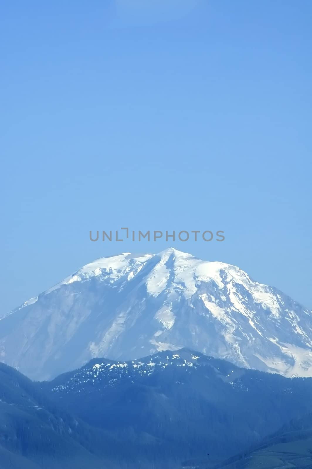 A vertical shot of Mount Rainier's peak from about 50 miles away, in summer.