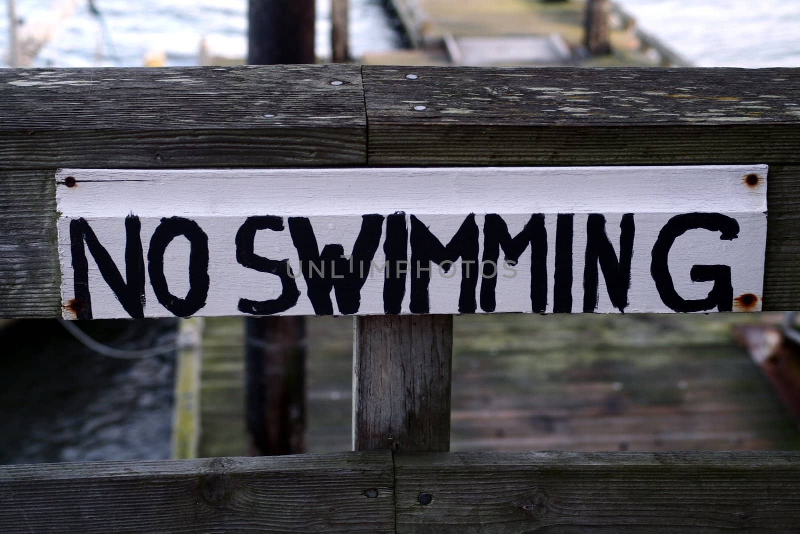 An old wood sign painted with No Swimming.