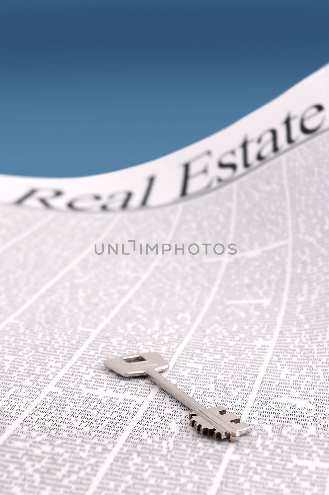 closeup of silver metallic key on real estate newspaper