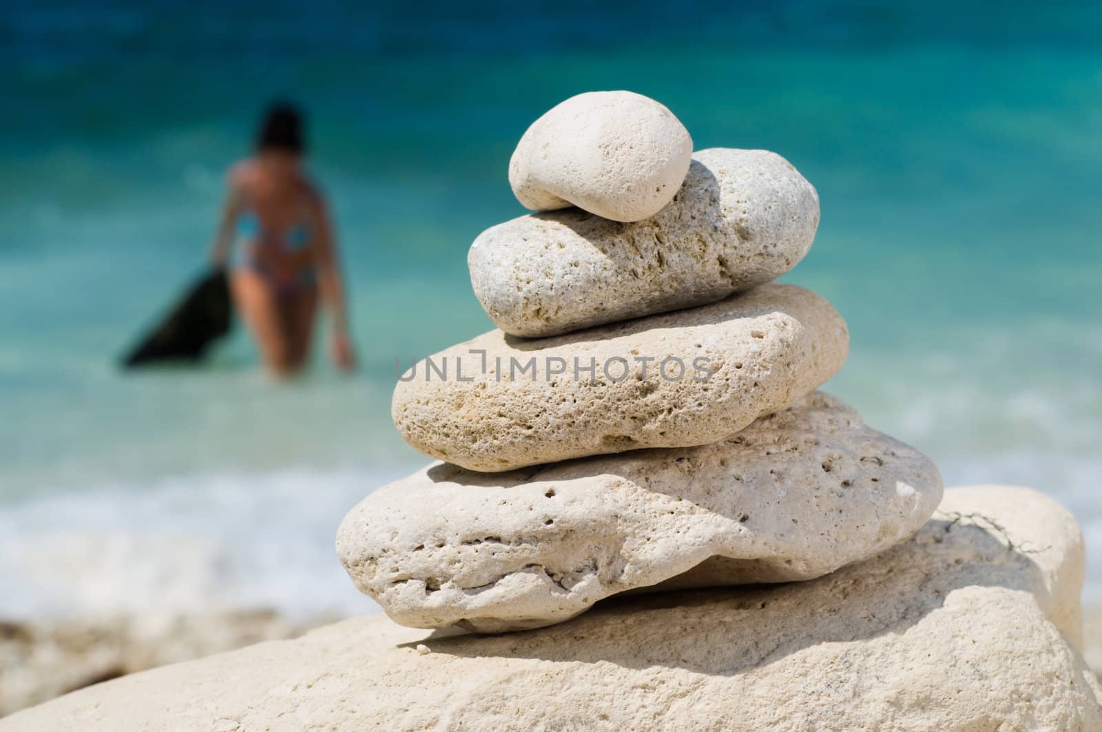 stacked pebbles on the beach, woman at blurred backgrond