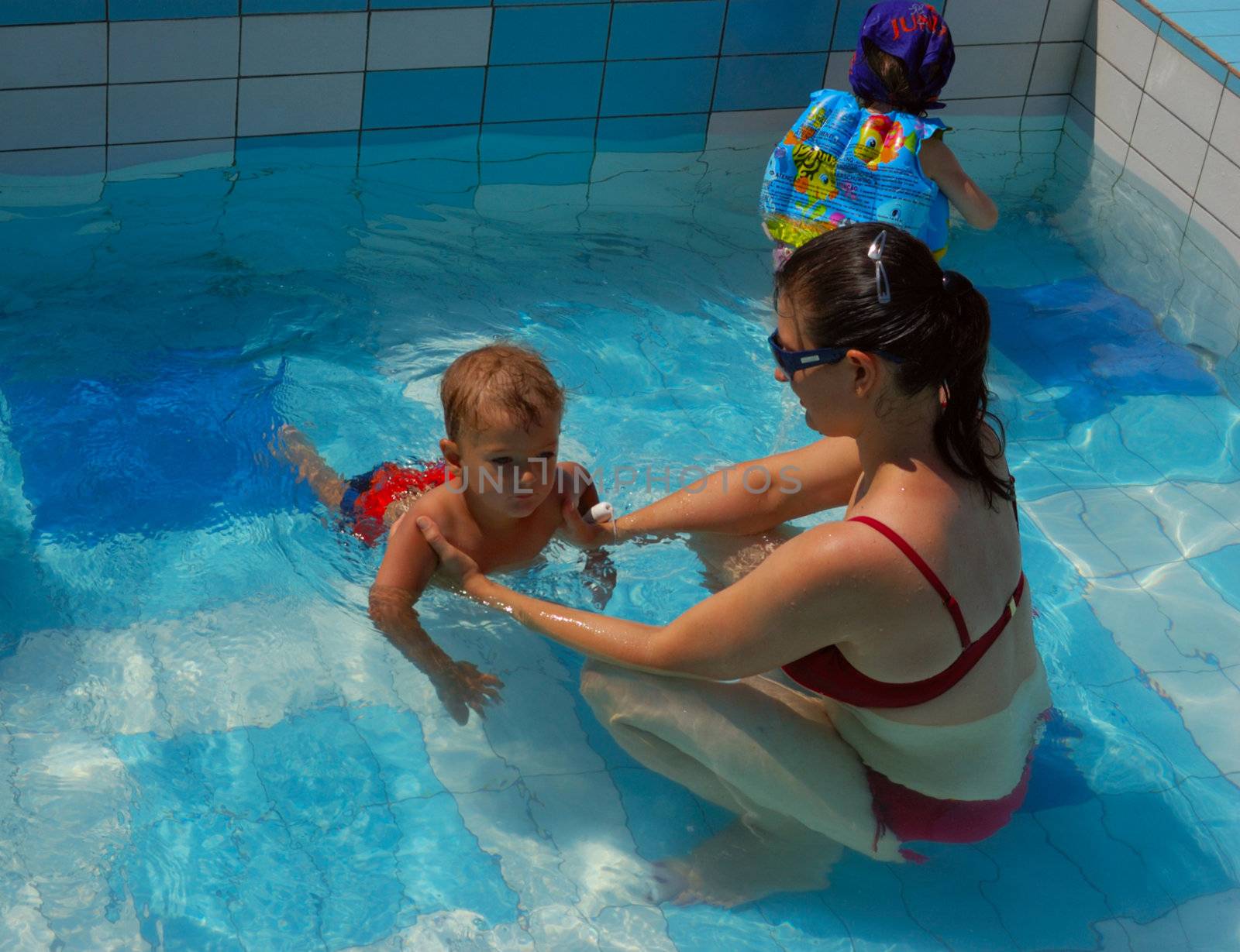 mother and little son at swimming pool having fun